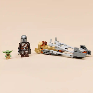 LEGO Star Wars minifigures and speeder bike set including The Mandalorian character in brown armor, green Grogu figure, tan and orange starfighter vehicle with white engines, and gray ship components against beige background