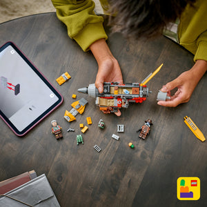Child in mustard yellow sweater building LEGO Cobb Vanth's Speeder set on wooden table with minifigures, bricks and instruction manual, tablet displaying building instructions visible, LEGO branding shown
