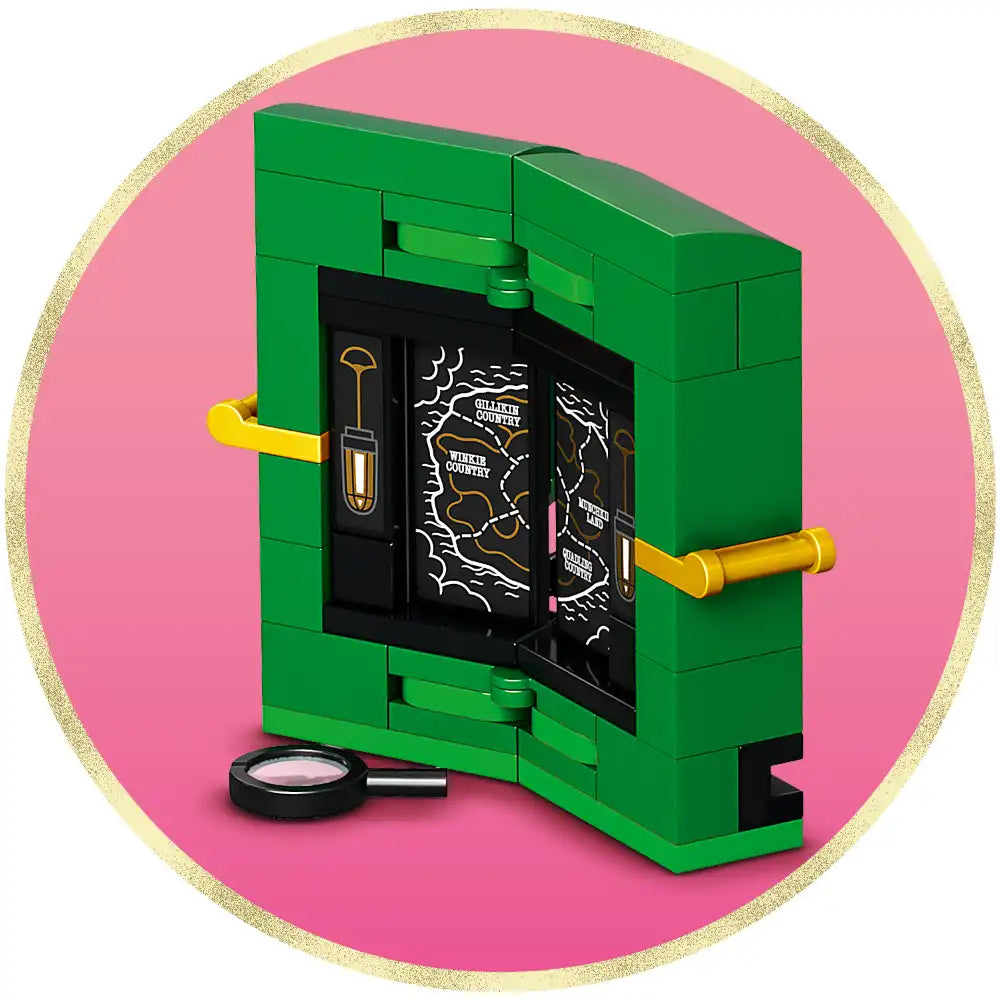 LEGO Wicked Emerald City and Kiamo Ko Castle building set 75689 featuring bright green brick structure with black interior details, yellow handle bars, magnifying glass accessory, and pink background with gold glitter border