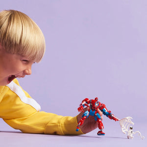 Child with blonde bob haircut wearing yellow jacket holding red and blue LEGO Spider-Man mech figure with small white skeleton minifigure on purple background
