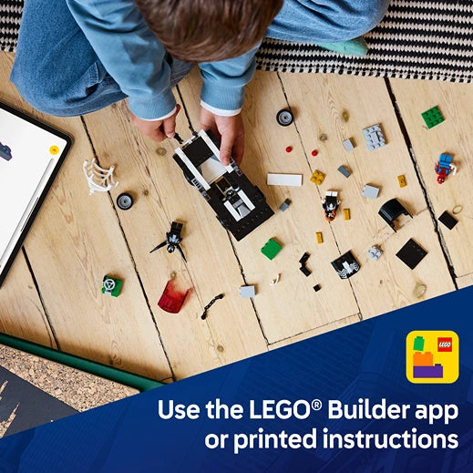 Child in blue clothing assembling LEGO Spider-Man vs. Venom Muscle Car set 76309 on wooden floor with scattered colorful LEGO pieces and building instructions, featuring LEGO Builder app promotional banner with yellow and blue logo