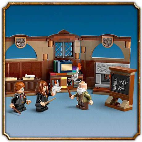 LEGO Hogwarts Castle Charms Class 76442 playset featuring a brown wooden classroom with blue arched windows, decorative shields, a blackboard, bookshelves, and three minifigures including a wizard with white beard against a blue background