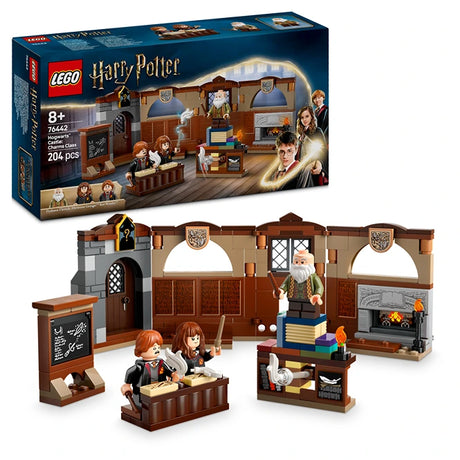 LEGO Harry Potter Hogwarts Castle Charms Class 76442 set featuring brown wooden classroom interior with minifigures, fireplace, desk, chalkboard and furniture pieces displayed with original packaging box