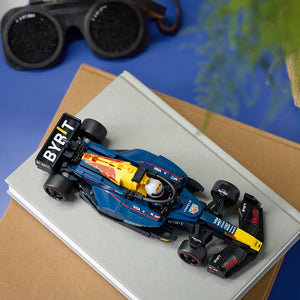 Blue and yellow LEGO Formula 1 race car model with Red Bull Racing branding displayed on white box with binoculars and map visible in background