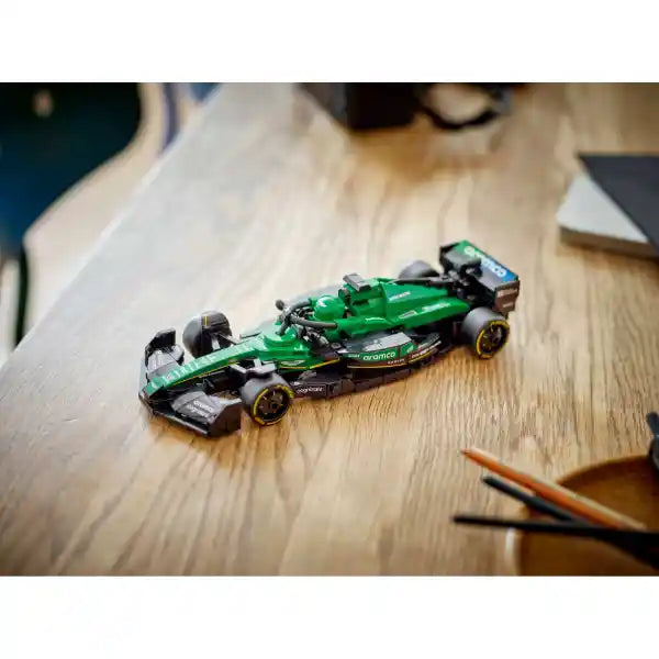 Green and black LEGO Aston Martin F1 race car model 77245 displayed on wooden desk surface with pencils and papers in background