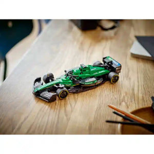 Green and black LEGO Aston Martin F1 race car model 77245 displayed on wooden desk surface with pencils and papers in background