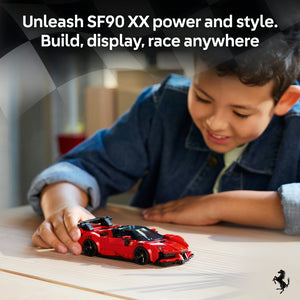 Young boy in blue jacket playing with red LEGO Ferrari SF90 XX sports car model on wooden table, showcasing buildable toy car with black accents and wheels