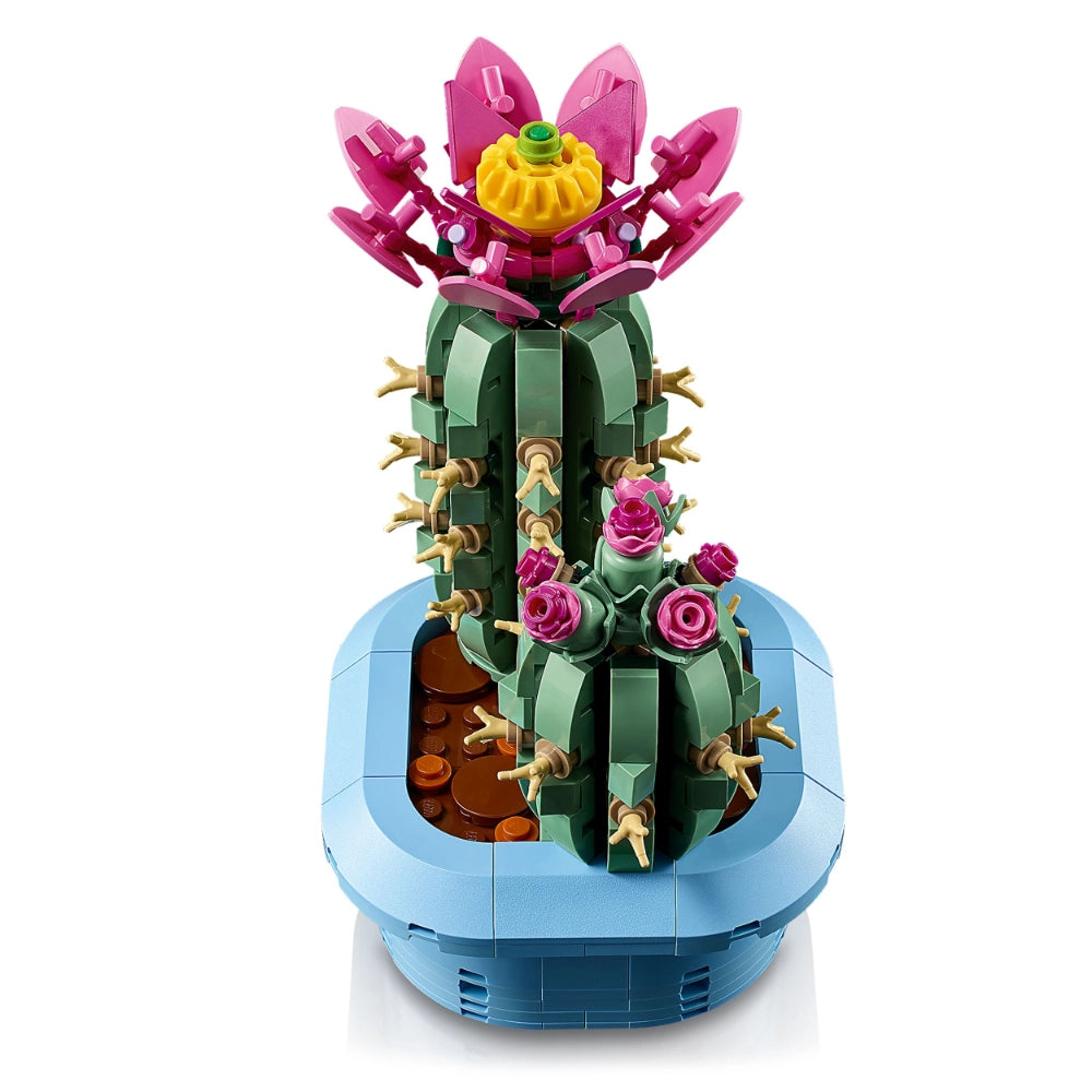 LEGO Flowering Cactus 10309 buildable plant set featuring a green segmented cactus stem with golden spines, pink and magenta blooming flowers with yellow center, and blue pot with brown soil, displayed against white background