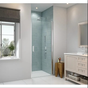 Modern bathroom featuring Merlyn 8 Series frameless pivot shower door in chrome with light blue tile surround, white subway tile walls, cream vanity cabinet, wooden accent stool, and large window with natural light