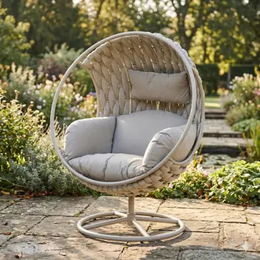 Wicker egg chair with gray cushions in a garden setting