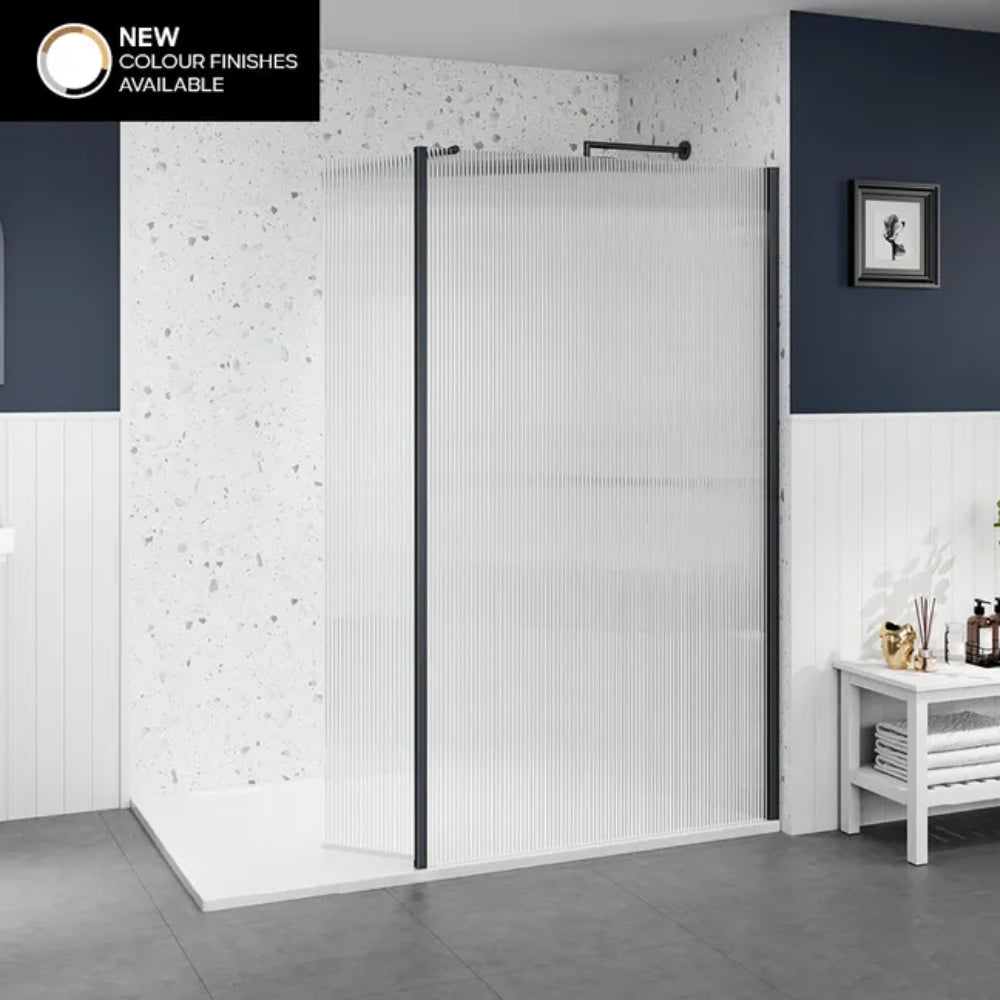 Merlyn 8mm wetroom shower panel with vertical ribbed glass and matte black frame finish, displayed in modern bathroom with white textured wall tiles, dark blue feature wall, white base tray, and chrome accessories