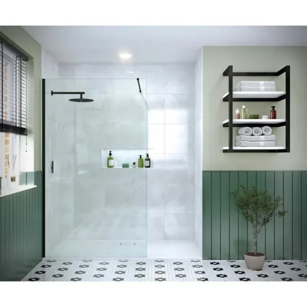 Modern bathroom featuring Merlyn 8mm wetroom panel with matte black frame, glass shower enclosure with black fixtures, green panelled walls, black metal shelving unit, patterned floor tiles, and potted plant