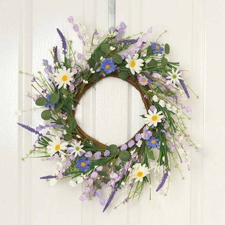 Round grapevine wreath decorated with white daisies, purple and blue flowers, lavender sprigs, and green foliage on white wooden background, 45cm meadow-style garden wreath