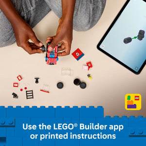 Overhead view of hands assembling a red and blue LEGO fire truck set with various colored bricks and components scattered on a beige surface, alongside a tablet displaying building instructions and the LEGO Builder app logo in the corner