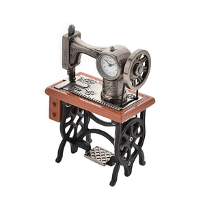 Widdop miniature decorative clock styled as a vintage sewing machine with metallic silver sewing head featuring working clock face, mounted on a wooden base with black cast iron treadle stand and footrest