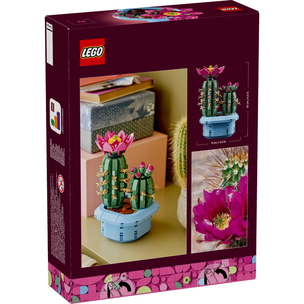 LEGO Flowering Cactus set 10309 box showing buildable green cacti with pink and magenta flowers in light blue pot displayed on shelf with books and real plants in background
