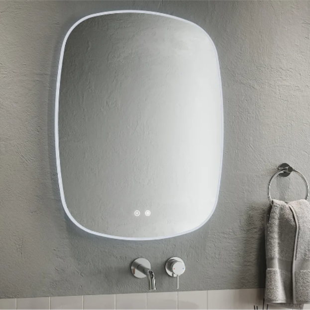 Modern Aqualla Trace LED bathroom mirror with rounded rectangular frame in white, mounted on grey textured wall above white subway tiles, featuring integrated LED lights and chrome wall-mounted faucet with towel ring