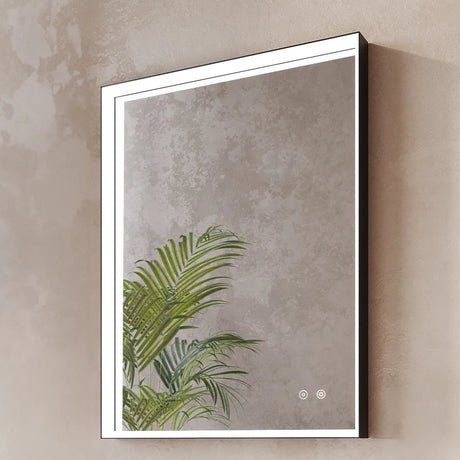 Modern rectangular LED-lit bathroom mirror with black frame and white border mounted on textured beige wall, featuring illuminated touch controls and reflection of green palm fronds in lower portion