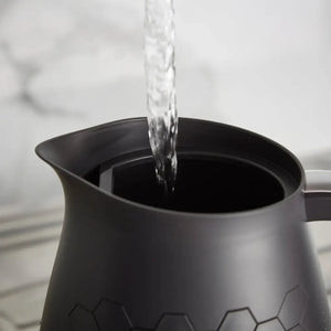 Water pouring into a black Morphy Richards Cassini jug kettle with a geometric hexagon pattern design on a white kitchen surface