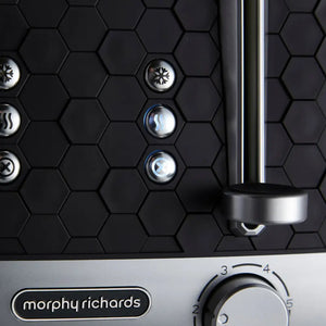 Morphy Richards Cassini 4 slice toaster in black with hexagonal pattern design, featuring illuminated control buttons for temperature and function settings, stainless steel accents, and chrome lever handle against white base panel