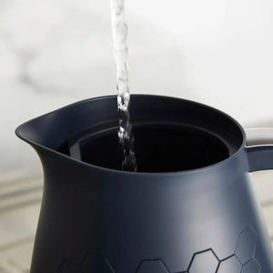 Water pouring into a black Morphy Richards Cassini 1.7 litre jug kettle with honeycomb pattern design on white background
