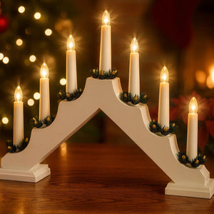 White wooden candlebridge with 7 LED candles in warm white light, featuring black and gold decorative elements, displayed on wooden surface with blurred golden bokeh lights in background