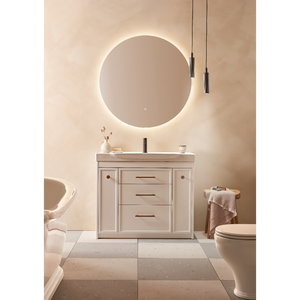 Modern bathroom vanity unit in matt white finish with integrated basin, three central drawers with bronze handles, flanked by cupboard doors, positioned beneath an illuminated circular mirror with warm LED backlighting, styled in a contemporary luxury bathroom setting with beige and cream tones