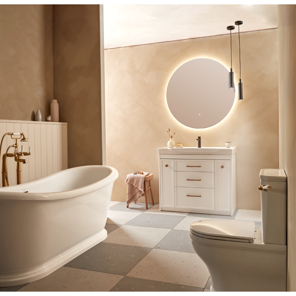 Modern bathroom interior showcasing Roper Rhodes Concierge Vanity Unit in Matt White with integrated basin, circular illuminated mirror, pendant lights, freestanding white bathtub, toilet, and warm beige tiled flooring in contemporary spa-style setting