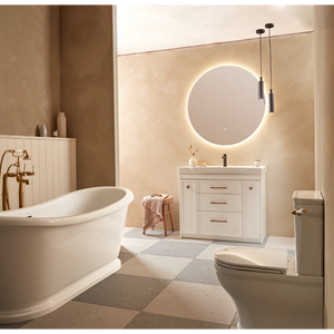 Modern bathroom interior showcasing Roper Rhodes Concierge Vanity Unit in Matt White with integrated basin, circular illuminated mirror, pendant lights, freestanding white bathtub, toilet, and warm beige tiled flooring in contemporary spa-style setting
