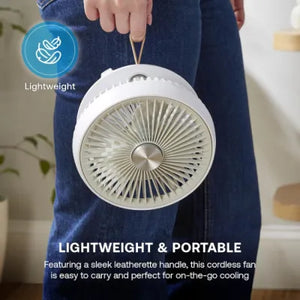 Person in dark blue jeans holding a white Dimplex cordless rechargeable 6-inch desktop fan with leatherette handle, demonstrating its lightweight and portable design with blue lightweight icon overlay