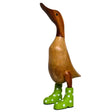 Wooden decorative duck figurine with dark brown head and natural wood body wearing lime green wellie boots with white polka dots, 30cm tall