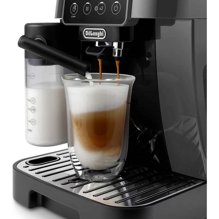 DeLonghi Magnifica Start bean to cup coffee machine in black and grey with milk frother, dispensing cappuccino into glass cup on drip tray with milk jug attachment visible