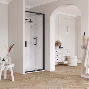 Modern bathroom featuring Flair ETO infold shower door with black frame and marble tiles, herringbone wood flooring, white pedestal sink, arched mirror, white storage dresser with black handles, and minimalist neutral decor