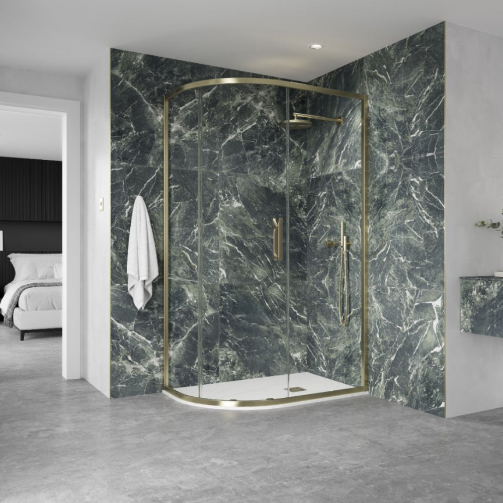 Modern brushed brass quadrant shower enclosure with curved glass doors against dark green marble-effect wall panels in a contemporary bathroom setting
