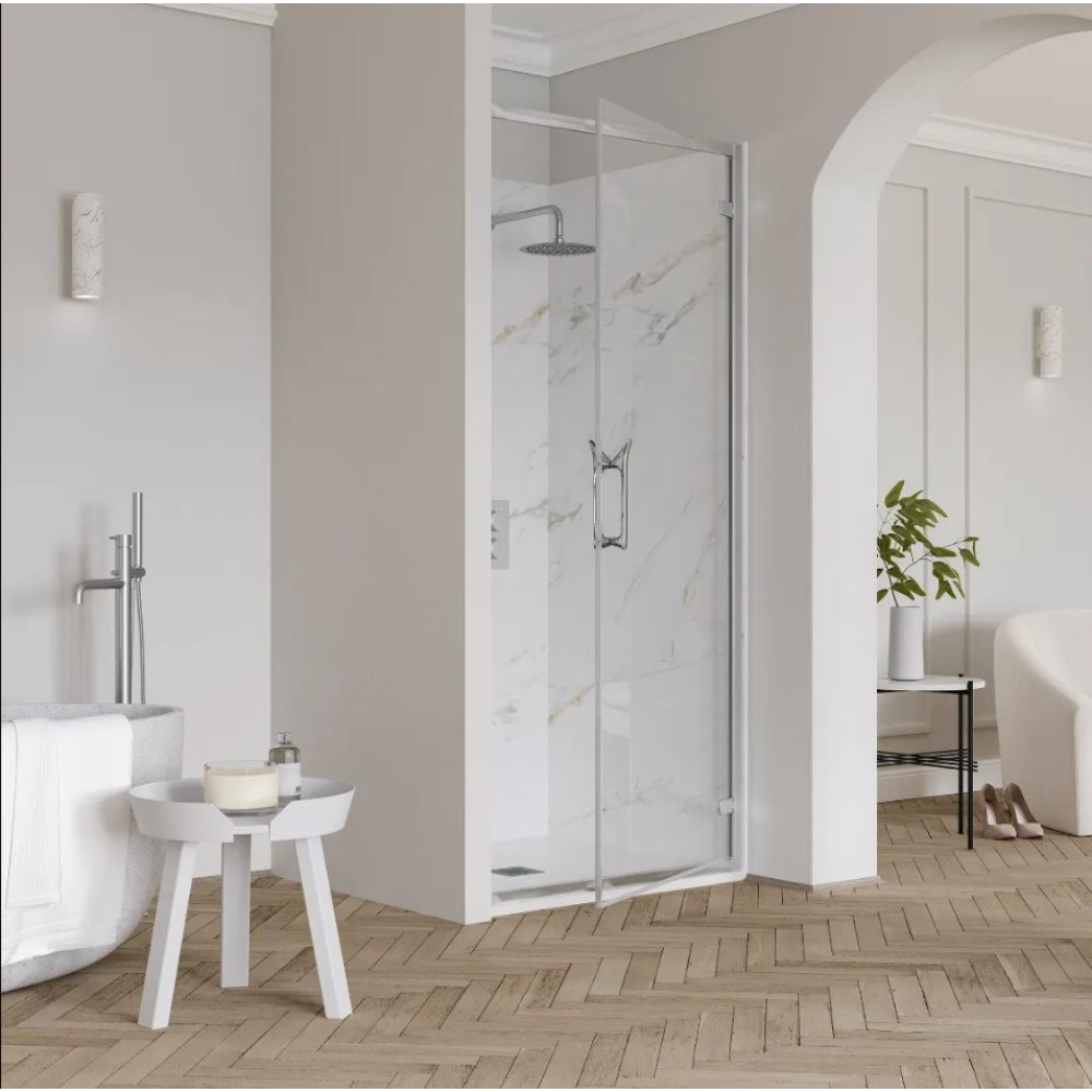 Modern bathroom featuring a chrome-framed hinged shower door with marble-effect tiled walls, white subway tile surround, wooden herringbone flooring, white freestanding bathtub, small white side table, and minimalist chrome fixtures in a contemporary spa-like setting