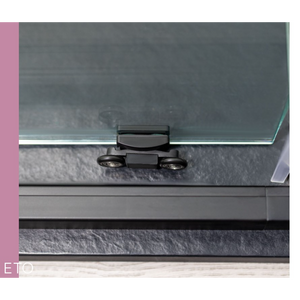 Close-up of Flair ETO sliding shower door hardware showing black frame with chrome handle and dual wheels mounted on glass panel against grey tiled bathroom wall