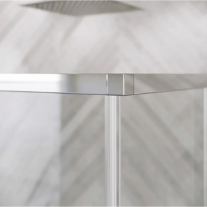 Close-up detail of chrome hinge mechanism on frameless glass shower door with white vertical profile and diagonal shadow pattern visible through clear glass panel