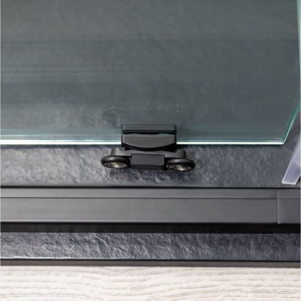 Close-up of Flair ETO Quadrant shower enclosure top bracket in matte black finish showing chrome hinges and clear glass panel against dark frame mounted on bathroom wall