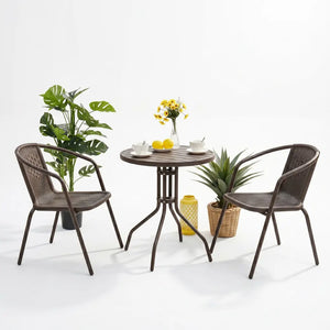 Euroactive rattan 2 seater balcony furniture set featuring two brown woven rattan chairs with curved armrests, a round dark wood pedestal table, potted green plants, yellow flowers in a vase, white teacups, and yellow decorative lemons on a white background
