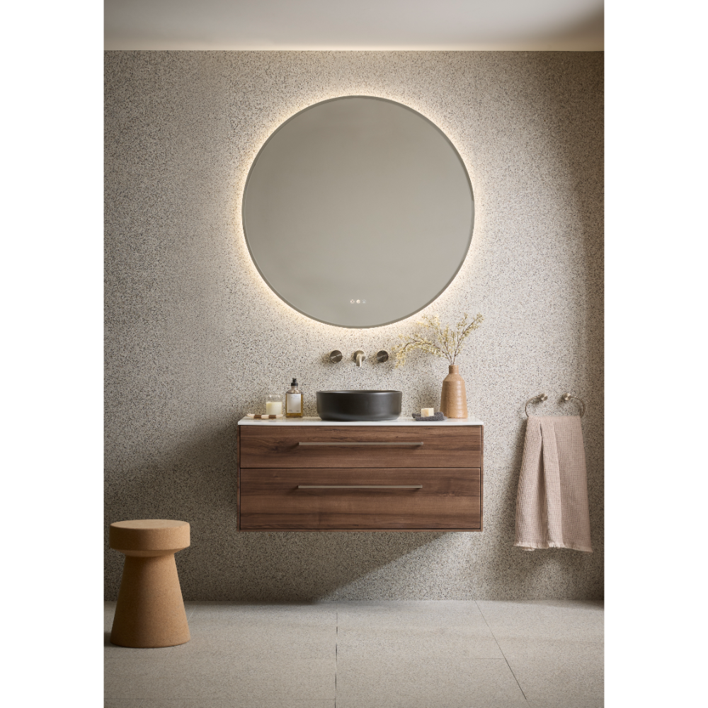 Modern bathroom vanity unit with walnut wood finish, wall-mounted design, featuring a black ceramic basin, illuminated circular mirror with LED backlight, brushed brass wall-mounted tap, complemented by neutral textiles and minimalist decor in contemporary spa-like setting