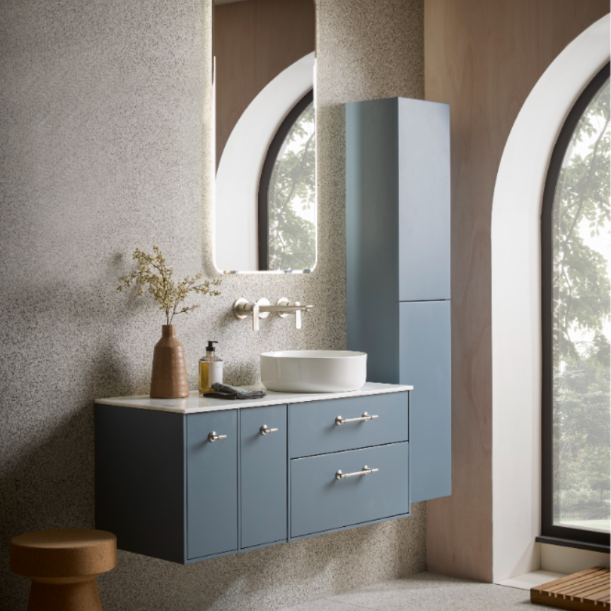 Modern bathroom vanity unit in Coniston Blue with white ceramic basin sink, wall-mounted design with drawers and cabinet storage, chrome handles, paired with tall matching storage tower, oval mirror with white frame, textured beige wall tiles, natural wood accessories and arched window frames