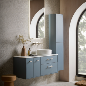 Modern bathroom vanity unit in Coniston Blue with white ceramic basin sink, wall-mounted design with drawers and cabinet storage, chrome handles, paired with tall matching storage tower, oval mirror with white frame, textured beige wall tiles, natural wood accessories and arched window frames
