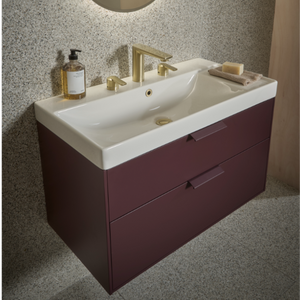 Modern burgundy vanity unit with white ceramic double sink, brass tap fittings, speckled grey splashback, and integrated storage drawers