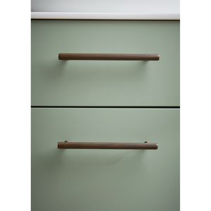 Sage green vanity unit with two horizontal bronze metal handles and black trim detail against white ceiling