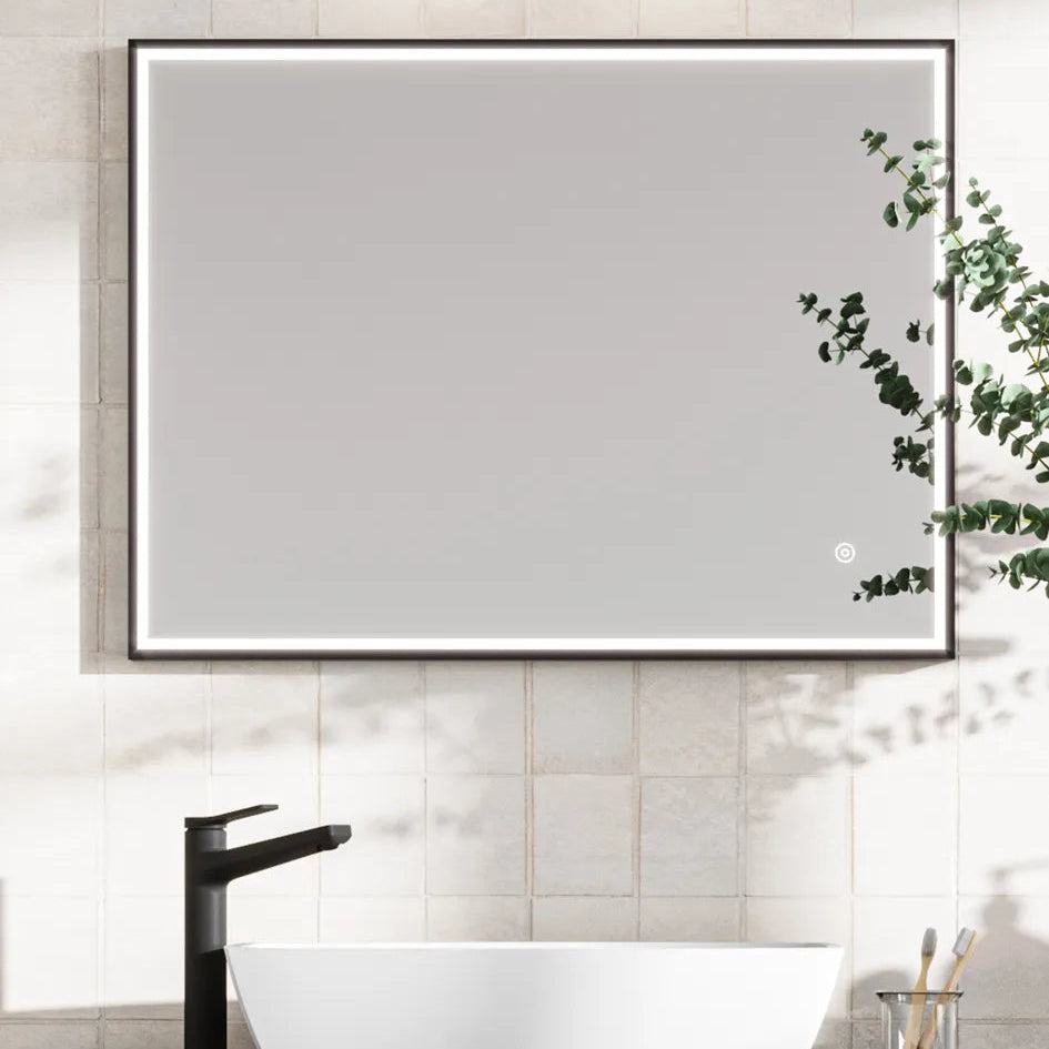 Modern LED bathroom mirror with black frame mounted on cream subway tiles above a white vessel sink and black faucet, featuring integrated lighting and trailing eucalyptus plant decoration