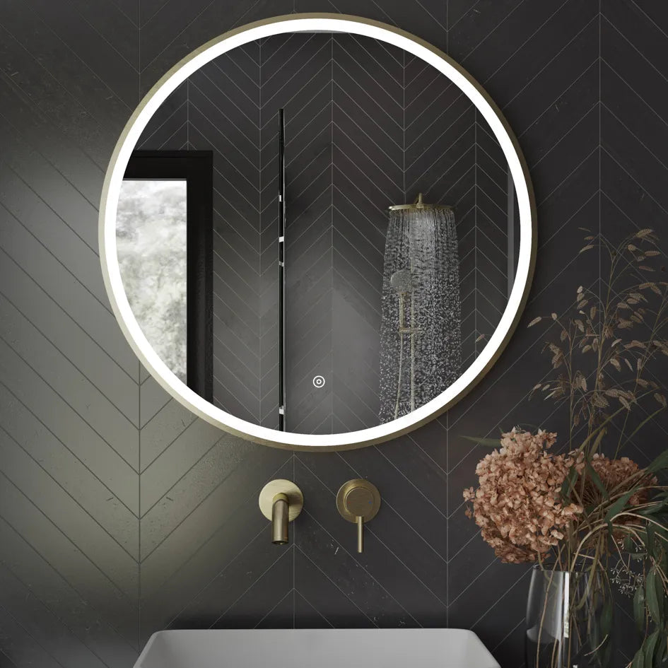 Aqualla Fuse Frame Round LED Bathroom Mirror 700mm in black with brushed brass fixtures mounted on dark herringbone tile wall above white basin with rainfall showerhead visible in reflection