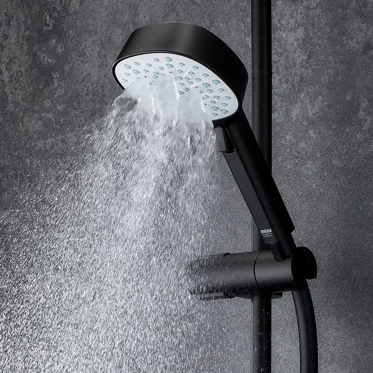 Mira Relate dual bar mixer shower in matt black with large round rainfall showerhead actively dispensing water against grey tile background