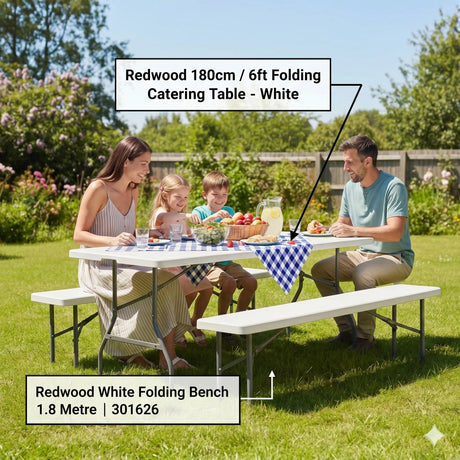 Family enjoying outdoor picnic at white Redwood 180cm folding catering table with matching white folding bench on grass garden setting with food, drinks and blue checkered tablecloth