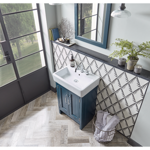Roper Rhodes Hampton vanity unit in slate grey with white rectangular sink, black countertop and geometric patterned backsplash tile, positioned in modern bathroom with herringbone wood-effect flooring, large windows, and decorative accessories