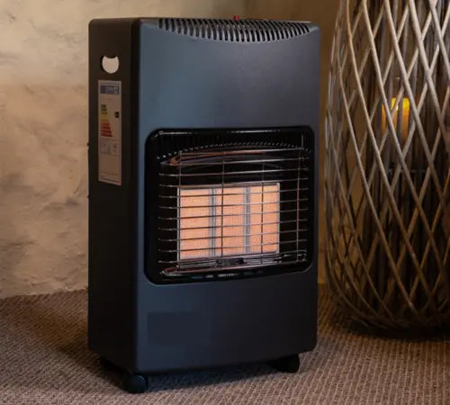 A black portable gas heater with a wire safety guard and visible orange flame element, standing on a textured carpet next to a woven basket holder.